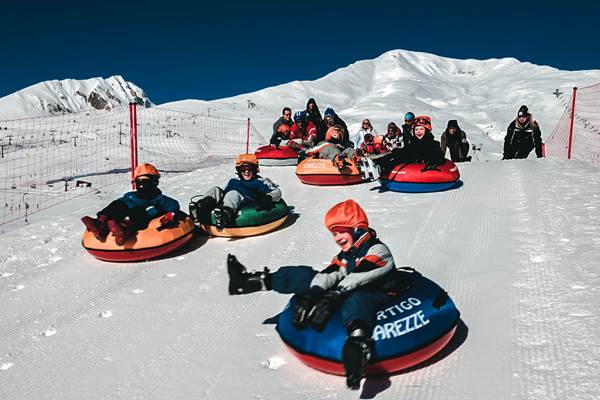 Bambini si divertono sui gommoni a Passo del Tonale, nel parco giochi sulla neve